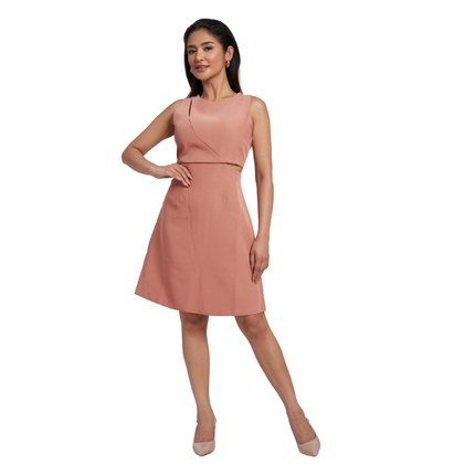 A woman modeling a sleeveless dusty pink A-line dress with a wrap-style V-neck bodice and a matching waist cutout, paired with nude heels against a plain white background.