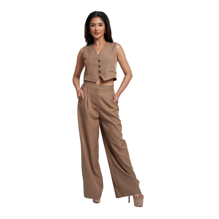 A woman modeling a matching two-piece outfit consisting of a sleeveless cropped vest with front buttons and high-waisted wide-leg trousers, in a solid taupe-brown color, set against a plain white background.