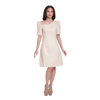 A woman modeling a light beige off-the-shoulder dress with puff sleeves and a knee-length skirt, paired with beige high-heeled sandals, set against a plain white background.