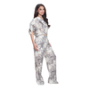 A woman modeling a short-sleeve jumpsuit with a white base and gray floral pattern, set against a plain white background.