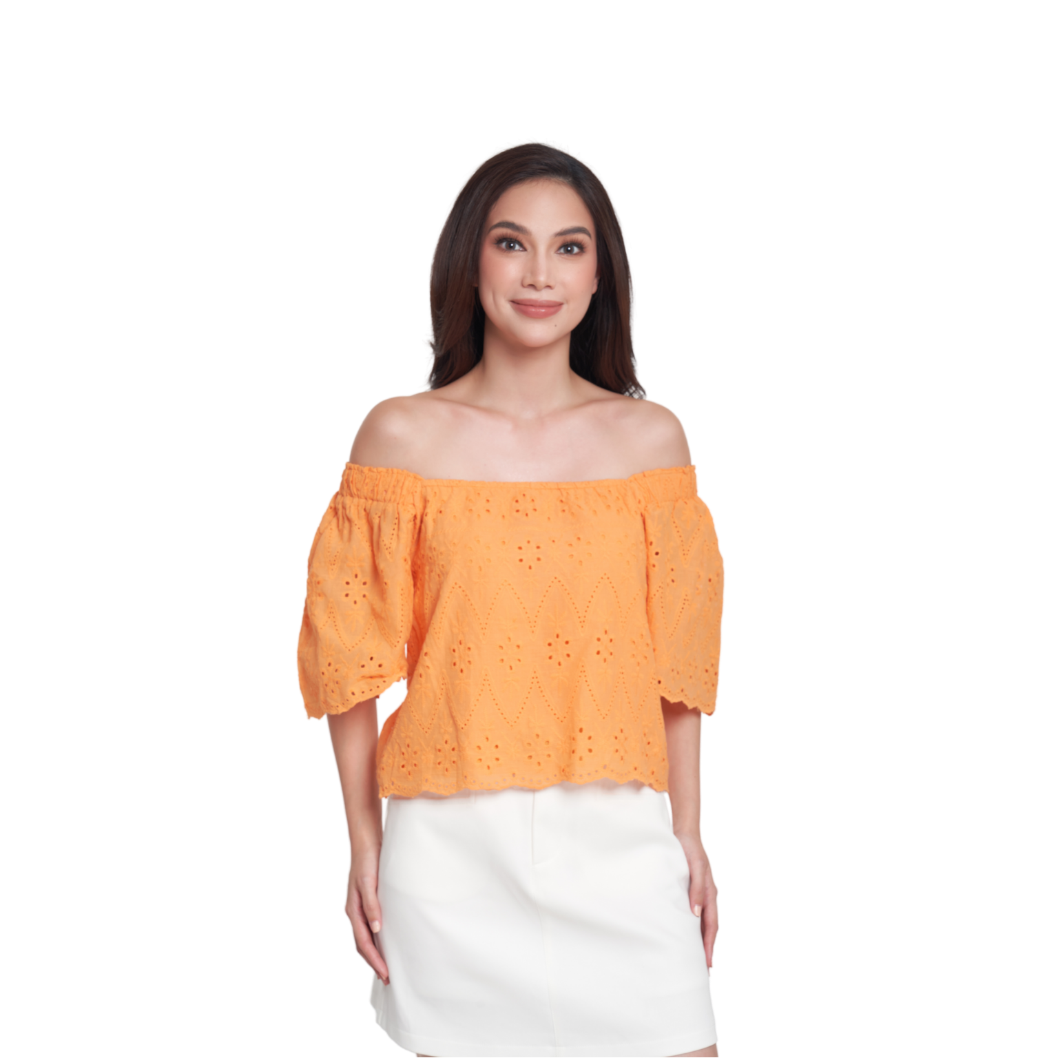 A woman modeling an off-the-shoulder eyelet top in a bright orange color, paired with a white skirt, against a plain white background.
