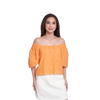 A woman modeling an off-the-shoulder eyelet top in a bright orange color, paired with a white skirt, against a plain white background.