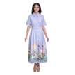 A woman modeling a light purple short-sleeve collared maxi dress with a matching belt and a colorful floral print along the hem, set against a plain white background.