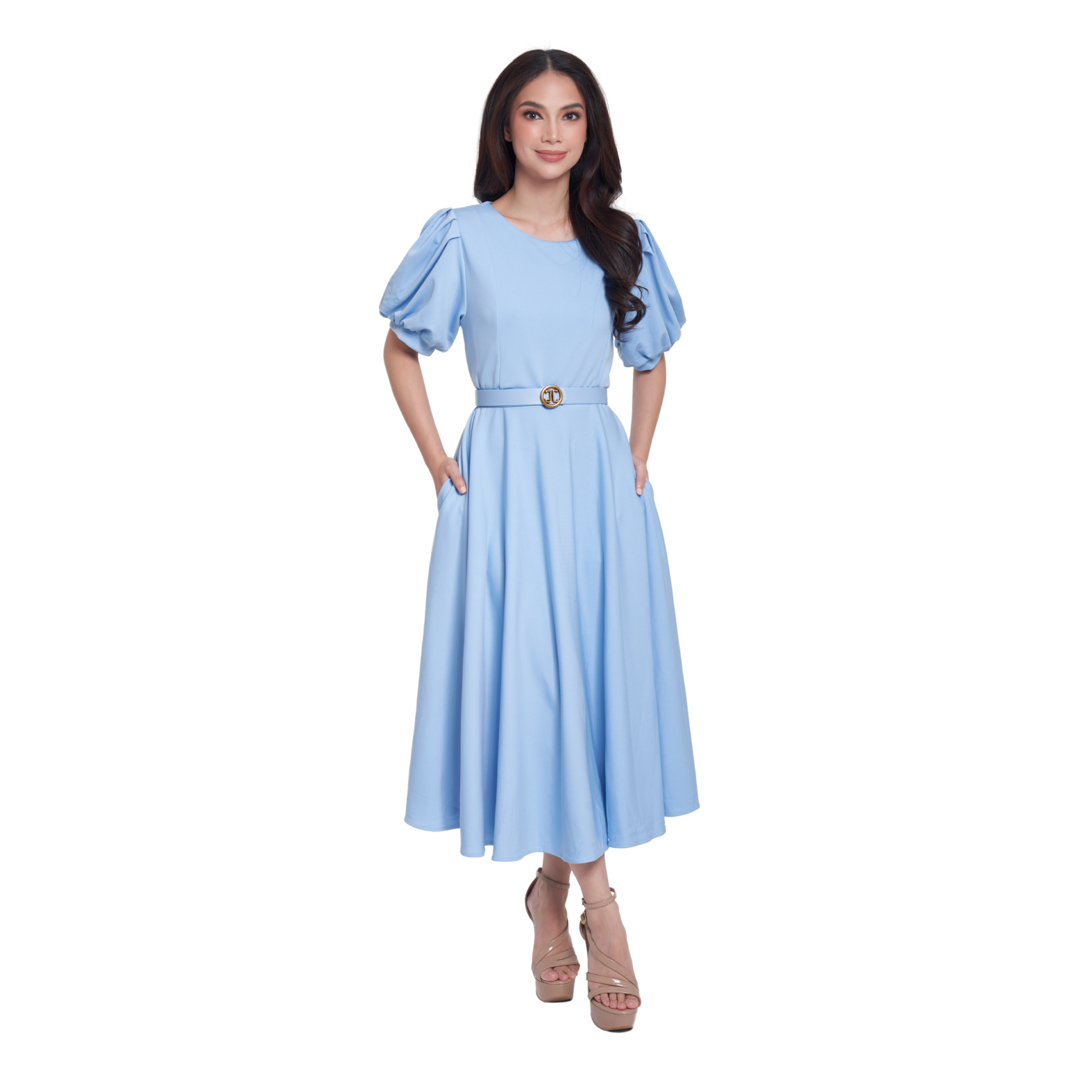 A woman modeling a light blue midi dress with puffed short sleeves, a matching waist belt with a gold-tone circular buckle, and side pockets, set against a plain white background.