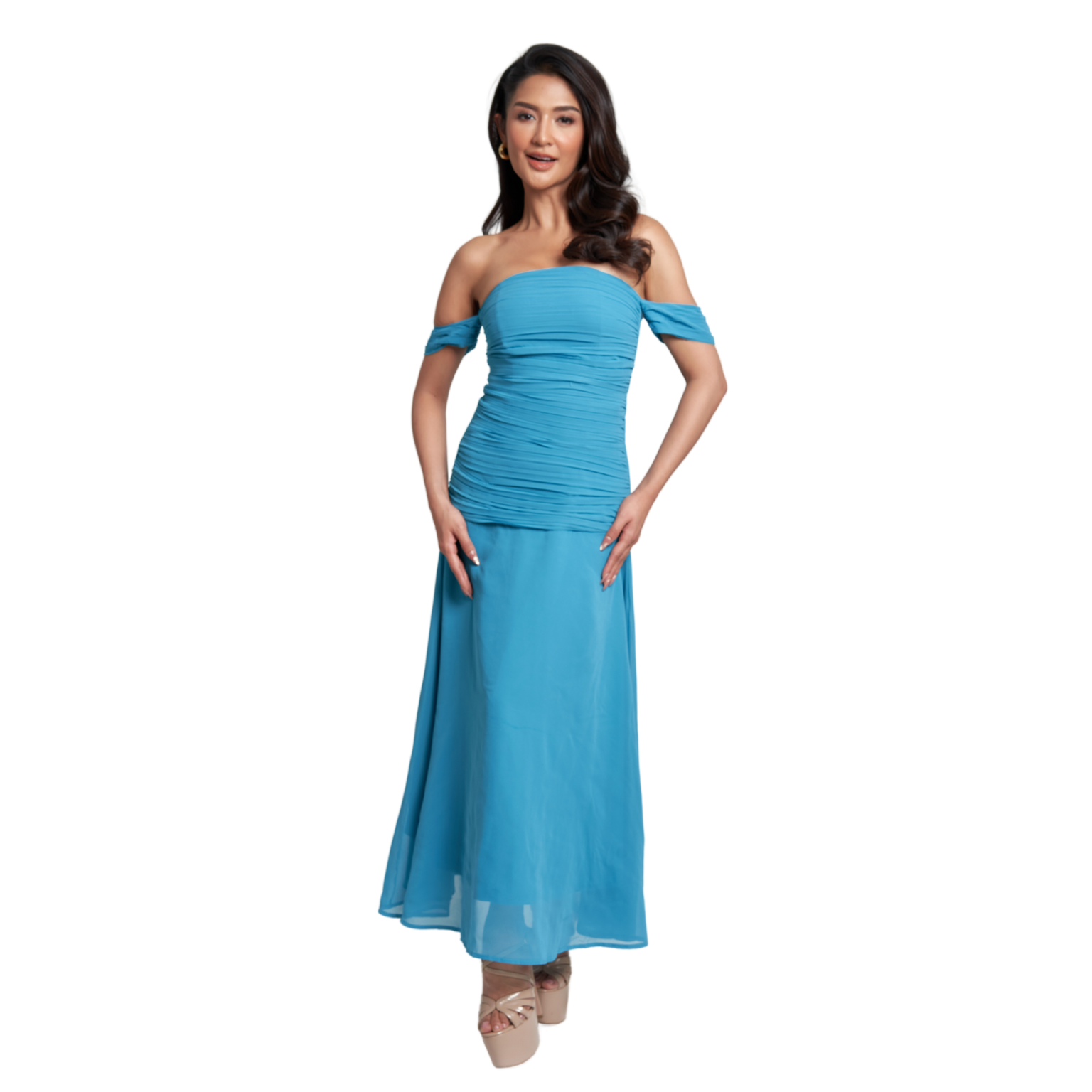 A woman modeling a bright turquoise blue off-the-shoulder maxi dress with a ruched bodice and flowing skirt, paired with beige platform sandals, set against a plain white background.