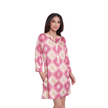 A woman modeling a pink and beige patterned tunic dress with three-quarter sleeves and a V-neckline, set against a plain white background.
